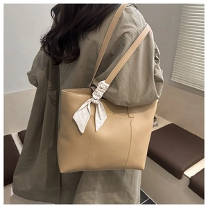 Dettaglio della borsa tote in pelle kaki chiaro con foulard di seta a scacchi