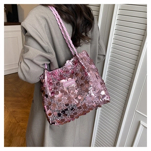 Dettaglio della borsa a tracolla con paillettes rosa e tracolla intrecciata sulla modella