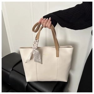 Dettaglio della borsa tote beige con manico marrone e sciarpa di seta a motivi geometrici
