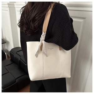 Dettaglio della borsa tote bianca con scritta e sciarpa di seta decorativa sul manico marrone