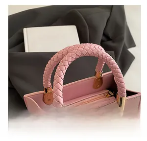 Detail van roze handtas met handvaten van gevlochten leer en zilveren sterversieringen