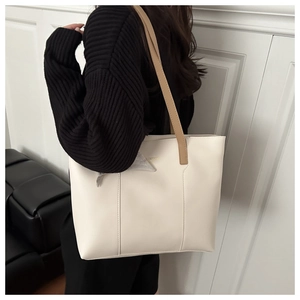 Dettaglio della borsa tote crema con sottili spalline kaki indossata su maglione nero