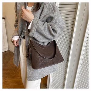 Close-up of dark brown lychee-patterned hobo bag with matching coin purse on model
