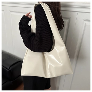 Dettaglio della borsa tote lucida bianco crema con ampia tracolla indossata da modella