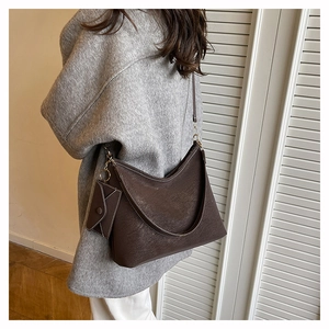 Detail view of dark brown tote bag with white contrast stitching and small pouch charm