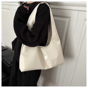 Dettaglio della borsa tote color crema in ecopelle indossata con maglieria nera chic