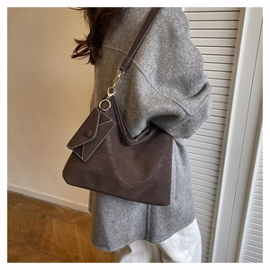 Detail of dark brown leather tote bag with small envelope pouch on a grey wool coat