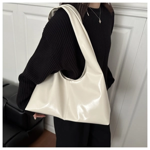 Dettaglio della grande borsa a tracolla minimalista color crema in pelle PU lucida