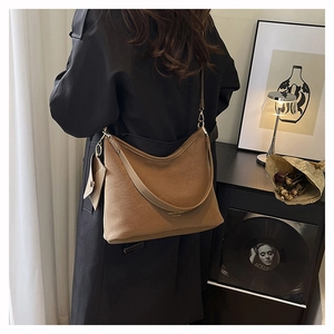 Brown leather hobo bag with matching small pouch worn over a long black winter coat