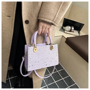 Detail of lavender square bag featuring silver star studs and woven handle texture
