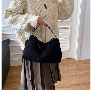 Dettaglio della borsa in ecopelliccia nera abbinata a un maglione bianco e gonna a pieghe