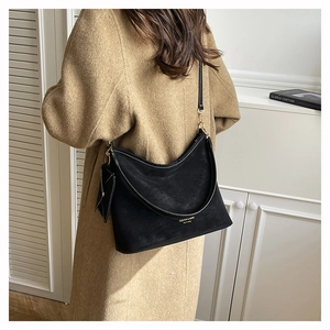 Detail of black suede tote bag featuring white contrast stitching and gold logo