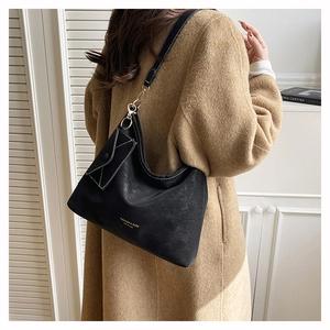 Detail of black pebbled leather tote bag with gold lettering and small envelope pouch
