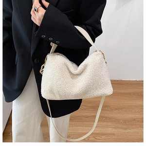 Dettaglio della borsa in pile bianco con cinturini in pelle e finiture in metallo dorato