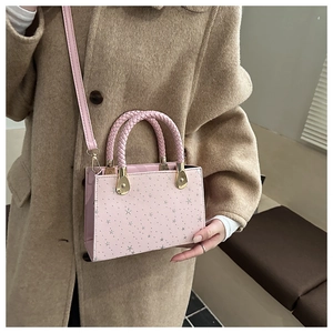 Detail van roze handtas met zilveren sterren, gevlochten handvat en gouden slot