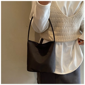 Détail d'un sac seau anthracite avec bandoulière porté par un mannequin au style minimaliste