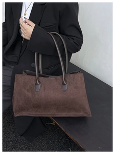 Detail of a dark brown suede tote bag featuring slim round handles for commuting