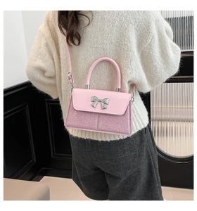 Detail of pink crossbody bag featuring glitter panels and silver metal bow clasp