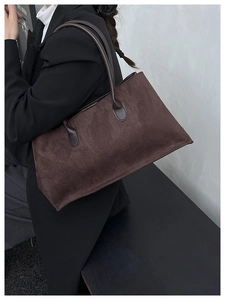 Detailed view of deep brown suede tote bag worn over the shoulder for a retro commuter look