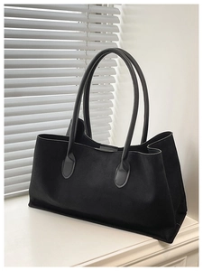 Detail of black suede tote bag with smooth leather handles for daily commute