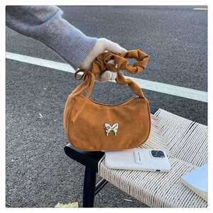Dettaglio borsa in pelle scamosciata marrone con tracolla increspata e farfalla argento