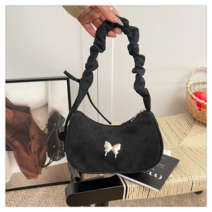 Dettaglio borsa hobo in camoscio nero con tracolla a pieghe e farfalla in argento