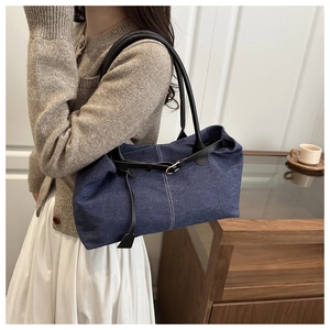 Dettaglio borsa tote in denim blu con cinturini in pelle e fibbia argento su modella