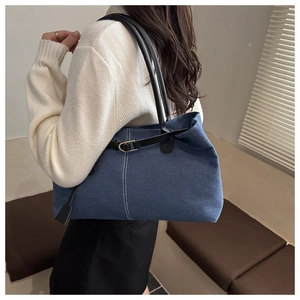 Dettaglio della borsa tote in denim blu con cinturini in pelle nera e fibbia