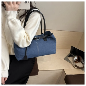 Dettaglio della borsa tote in denim blu con tracolla nera e cuciture bianche