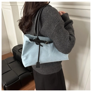 Dettaglio della borsa tote in tela azzurra con manici in pelle nera e fibbia in metallo
