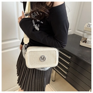 Dettaglio della trama intrecciata e del logo M in metallo sulla borsa beige a tracolla
