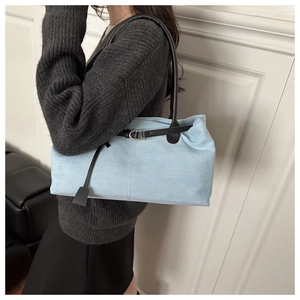 Dettaglio della borsa sottobraccio in denim azzurro con cinturini in pelle nera e fibbia
