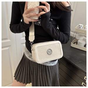 Dettaglio laterale della borsa a tracolla beige intrecciata con logo M argento