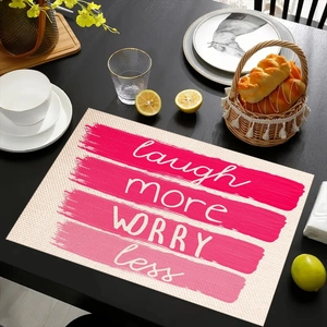 Modern linen placemat with laugh more worry less quote on a black wooden table