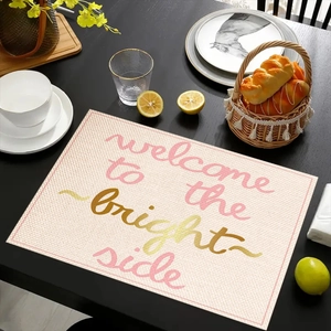 Close-up of linen placemat with pink Welcome to the Bright Side text on a black table
