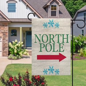 Detailed view of North Pole Christmas garden flag hanging on a black metal stake outdoors