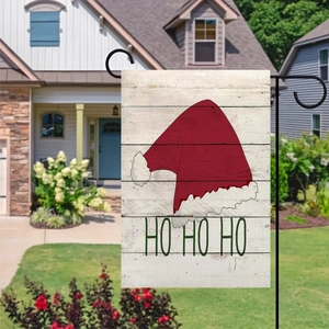 Detail of Christmas garden flag with HO HO HO text on a black metal stake in a sunny yard