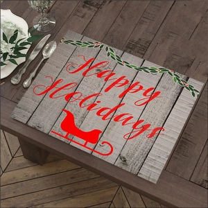 Sottopiatto natalizio con scritta Happy Holidays e slitta rossa su tavolo in legno