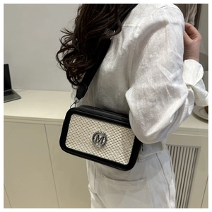 Detail view of woven crossbody bag with black leather trim and wide shoulder strap