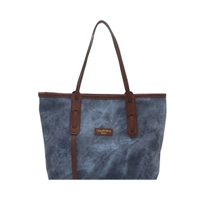 Blue denim tote bag with brown leather handles and brand patch for casual daily commute