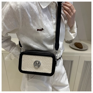 Detail of crossbody camera bag featuring straw texture, letter M logo and wide strap
