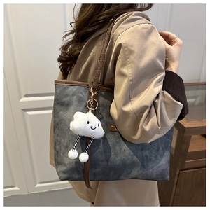 Detail of grey textured tote bag with brown leather straps and cute cloud charm