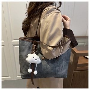 Detail of charcoal grey canvas tote bag with brown leather handles and a cute cloud charm