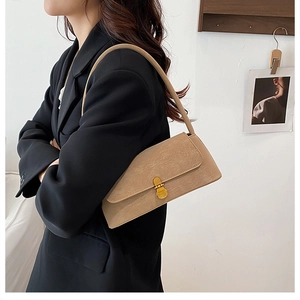 Dettaglio di una borsa baguette in pelle kaki con fibbia dorata indossata da una modella