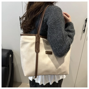 Detail of minimalist cream tote bag showing suede texture and brown leather logo tag
