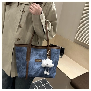 Detailed view of blue washed texture tote bag with leather trim and cloud charm