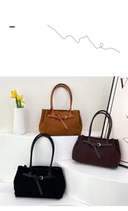 Detail of suede tote bags in brown and black with slim straps and buckle accents
