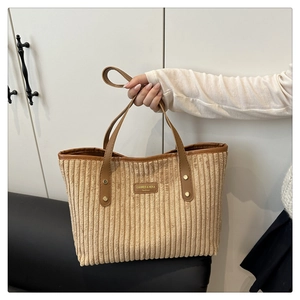Dettaglio della borsa tote in velluto a coste beige con rifiniture in pelle marrone e texture