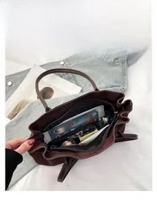 Spacious interior of dark brown suede tote bag showing tablet and daily essentials