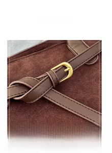 Detailed close-up of dark brown suede leather bag with vintage gold metal buckle